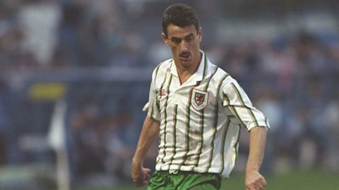 Ian Rush in action for Wales, wearing a white away shirt with red and green pinstripes