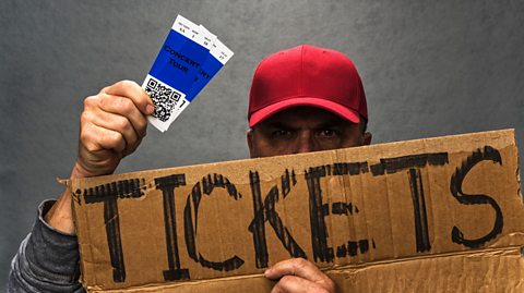 An image of a tout selling tickets from behind a cardboard sign