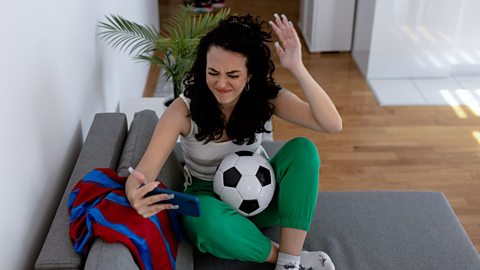 An image of a frustrated football fan watching the game on her mobile phone