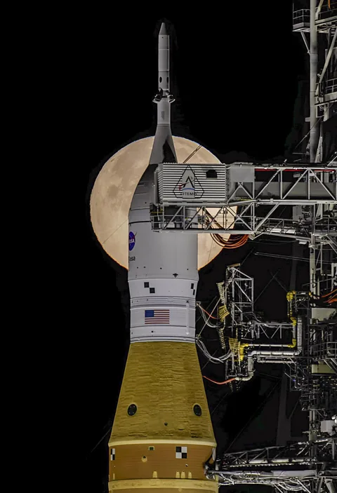 Nasa/ Jim Ross The Moon visible behind the Orion spacecraft atop the SLS rocket system at the launchpad (Credit: Nasa/ Jim Ross)