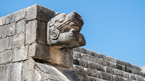 A jaguar's head made from stone on an ancient Maya temple.