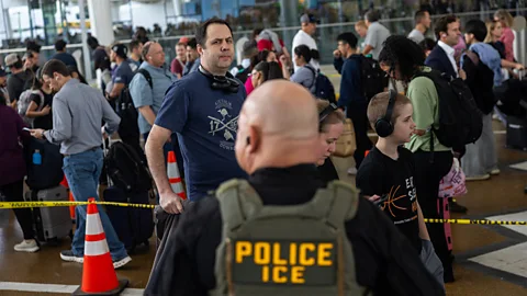 Getty Images A US Immigration and Customs Enforcement officer from behind, with travellers queueing up in the airport (Credit: Getty Images)