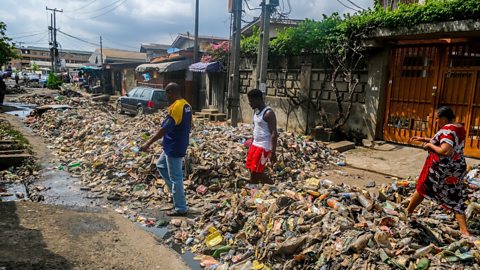 Waste collectors clean streets off of garbage piles caused by heavy rainfall in Lagos