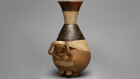 Bottle in the shape of a person carrying a load using a tumpline.