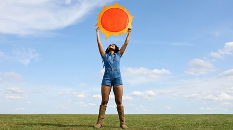An illustration of a man in shorts and a t-shirt, sitting on a chair and bathed in the glow of a gigantic green anglepoise lamp