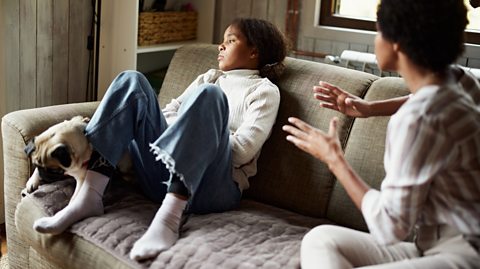 Mum tries to talk to angry teen daughter on sofa