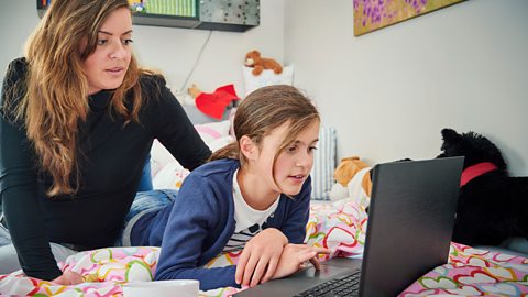 Mum watching over daughter's shoulder.