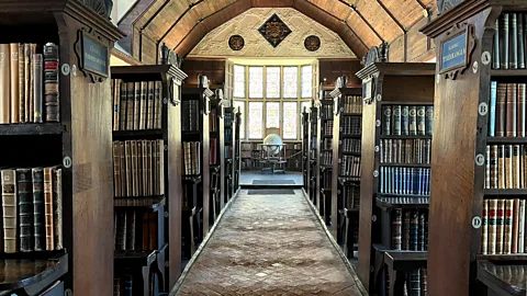 Courtesy of the Warden and Fellows of Merton College Oxford A walkway in the library of Merton College Oxford, lined with rows of bookcases and a globe at the end (Credit: Courtesy of the Warden and Fellows of Merton College Oxford)