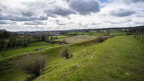 Richard Collett A grassy ridge at Old Oswestry Hillfort overlooks fields and the town of Oswestry under a cloudy sky (Credit: Richard Collett)