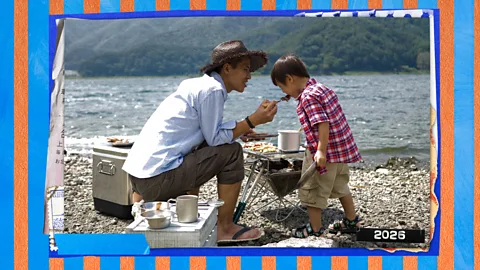 Serenity Strull/ BBC/ Getty Images A father sitting down and feeding his young son along a lake, with a blue and orange scrapbook texture behind them (Credit: Serenity Strull/ BBC/ Getty Images)