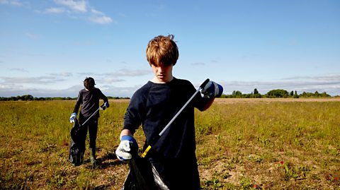 teenage boys pick litter in a field for work experience