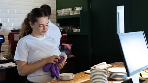 Girl cleans cups in a cafe