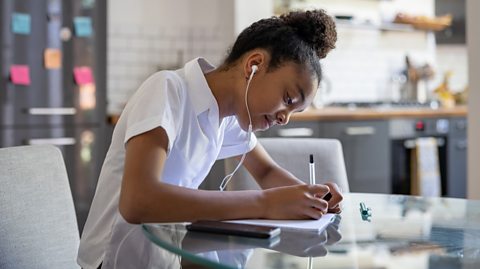 teenage girl studies for exams while listening to music