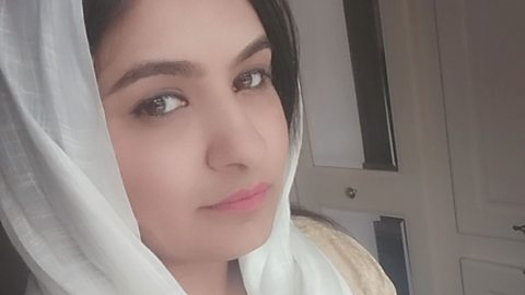 A close-up of a woman, Jamila, who is wearing a white head-scarf