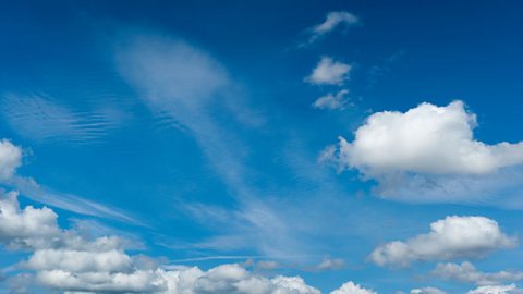 A landscape image of a bright blue sky with several fluffy clouds. 