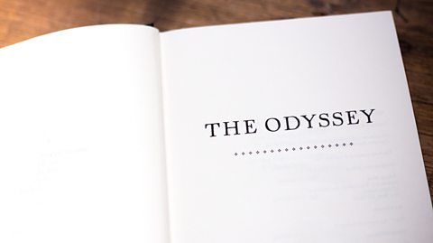 An open book resting on a desk, which shows the inner title page of The odyssey.