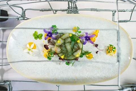 Courtesy of Sungani Restaurant An elegant fish mould on a white plate surrounded by yellow and purple edible flowers (Credit: Courtesy of Sungani Restaurant)