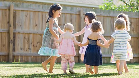 A group of six children, playing together on a lawn.