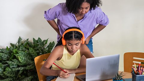 mother looks over daughter's shoulder as she revises