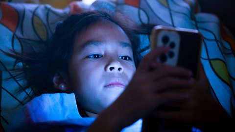 girl in bed totally lost in smartphone