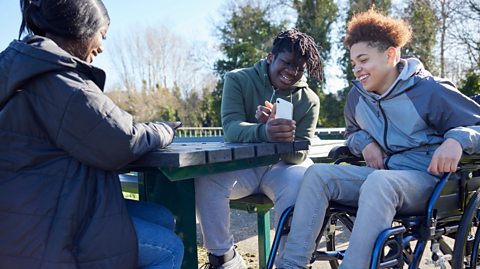 young people in park laughing at social media post