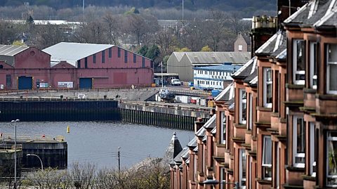 Industrial units surround a dock in background of a row of tenement housing