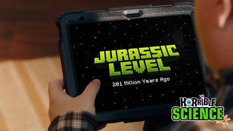 Image of game on tablet showing 'Jurassic Level' in capital green letters. Underneath it says 201 million years ago in white. The Horrible Science logo is in the bottom right corner. 