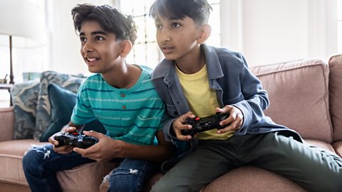 11-year-old boys on sofa with games consoles
