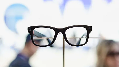 Getty Images A woman wearing black-framed glasses peers over an orange menu in a café (Credit: Laura Hall)