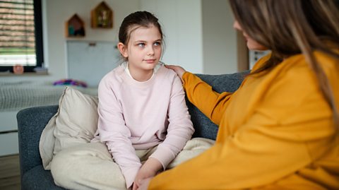 Caring Mum comforts tween daughter on sofa