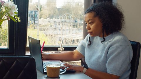 Marisha looking at her laptop, making notes with a cup of tea. 