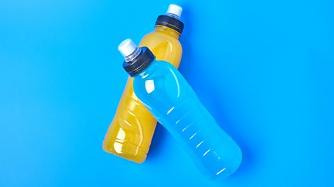 Two electrolyte drinks against a blue background.