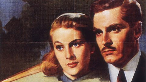 The colour movie poster for the 1940 adaptation of Daphne du Maurier's 'Rebecca'. The two main characters, Maxim de Winter and Mrs de Winter, stand with their heads close together looking off to the left. Maxim looks serious while his wife wears a faint smile.