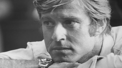 A black and white close-up photograph of actor Robert Redford. He has light coloured hair and is looking seriously off to the left of the camera.