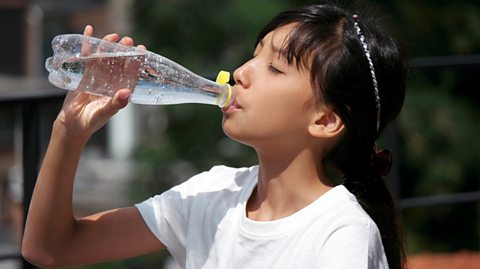 Girl drinks from water bottle as sun beats down