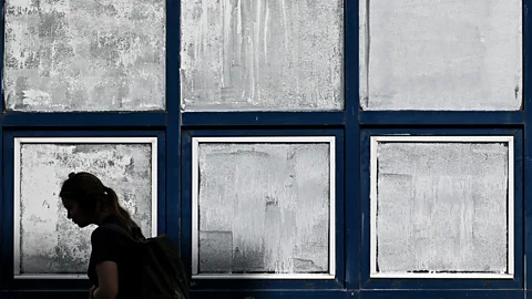 Getty Images A silhouette of a woman walking past windows painted with white chalk paint (Credit: Getty Images)