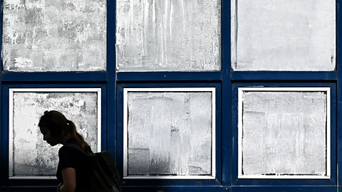 Getty Images A silhouette of a woman walking past windows painted with white chalk paint (Credit: Getty Images)