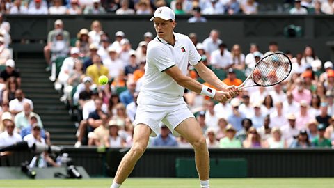Jannik Sinner playing tennis on a grass court.