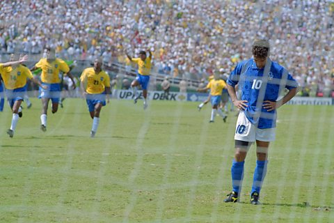 Italy's Roberto Baggio with his head down as Brazil players leap for joy behind him