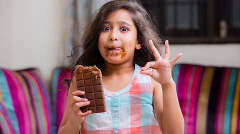 Girl eating a bar of chocolate.