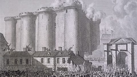 A black and white drawing depicting the Bastille prison in Paris on 14 July 1789. It's a large brick fortress made up of eight round towers with a gate house to the right. Beneath it, a mob of people is congregated ready to storm the building. 