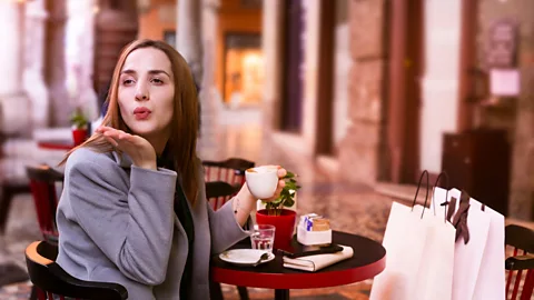 Alamy A young girl drinks coffee in a street cafe and blows a kiss (Credit: Alamy)