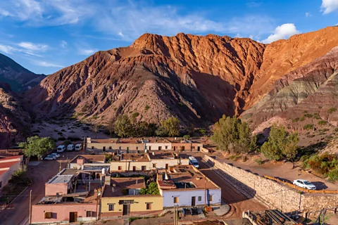 Getty Images The Cerro de los Siete Colores' colourful slopes tower over the village of Purmacara (Credit: Getty Images)