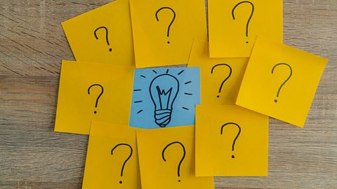 Question marks drawn on Post-It notes, surrounding a lightbulb drawing in the centre.