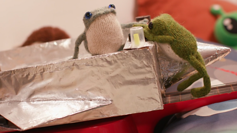 A cardboard spaceship covered in tin-foil, with Froglets on it