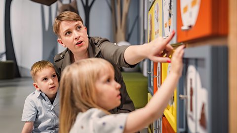 Mum and two young children use interactive exhibits in a gallery or museum