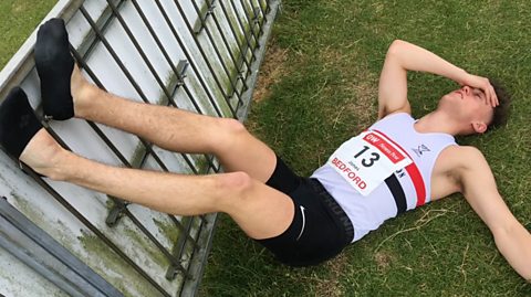 Elliot Jones lying on a grassy field following a race