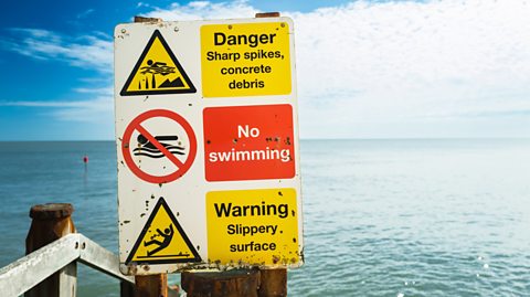 Signs highlight danger and no swimming on a UK beach