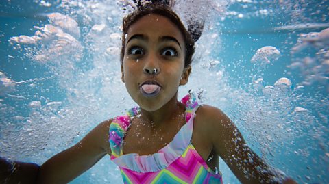 Girl pokes tongue out underwater in a pool