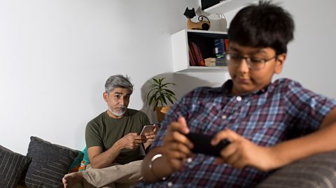 Father looks concerned as son plays games.